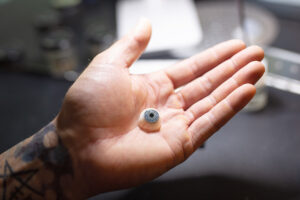 Ocularist Dwayne Collins holding a bespoke custom replacement prosthetic eye
